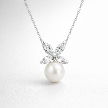 Studio view of a silver tone butterfly shaped pendant featuring marquise cut cubic zirconia stones forming the wings and a suspended round white pearl.