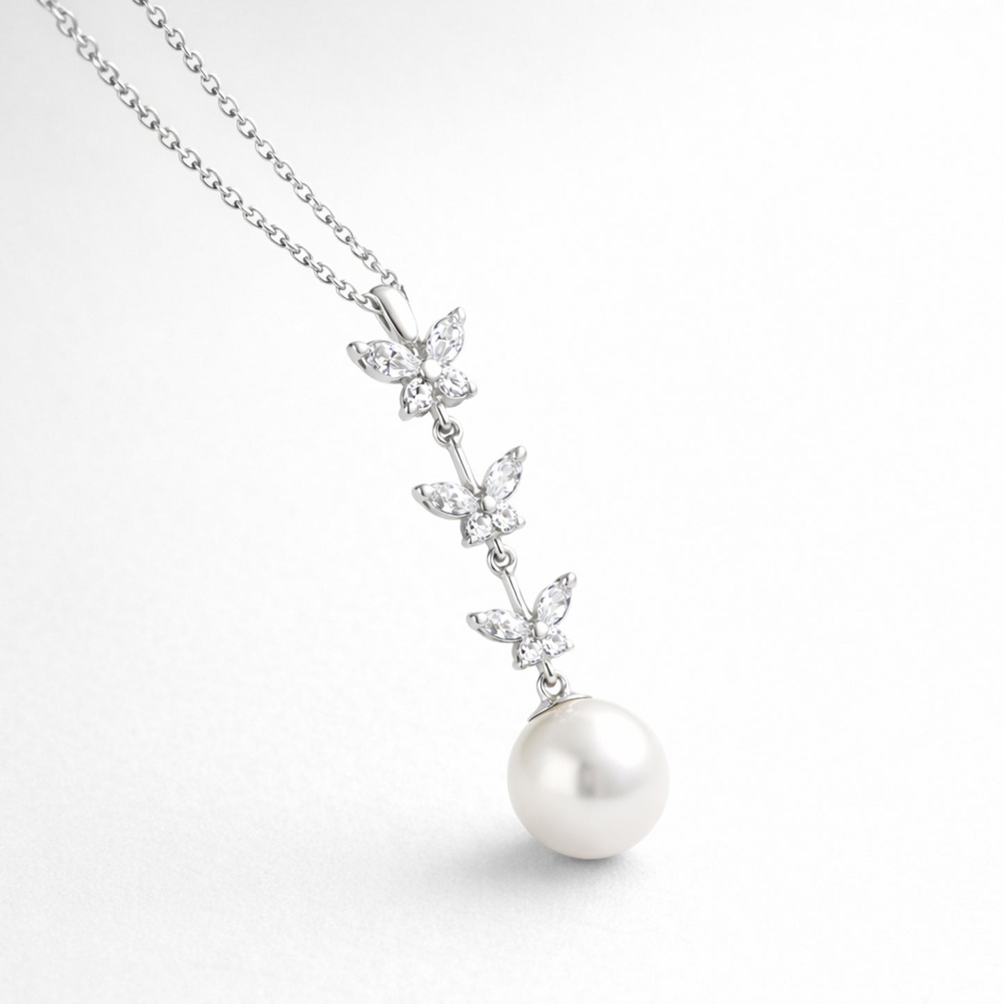 Angled studio view highlighting the vertical butterfly arrangement with marquise cut cubic zirconia stones and a suspended pearl.
