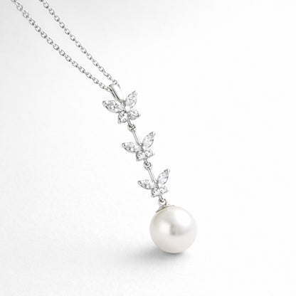 Angled studio view highlighting the vertical butterfly arrangement with marquise cut cubic zirconia stones and a suspended pearl.
