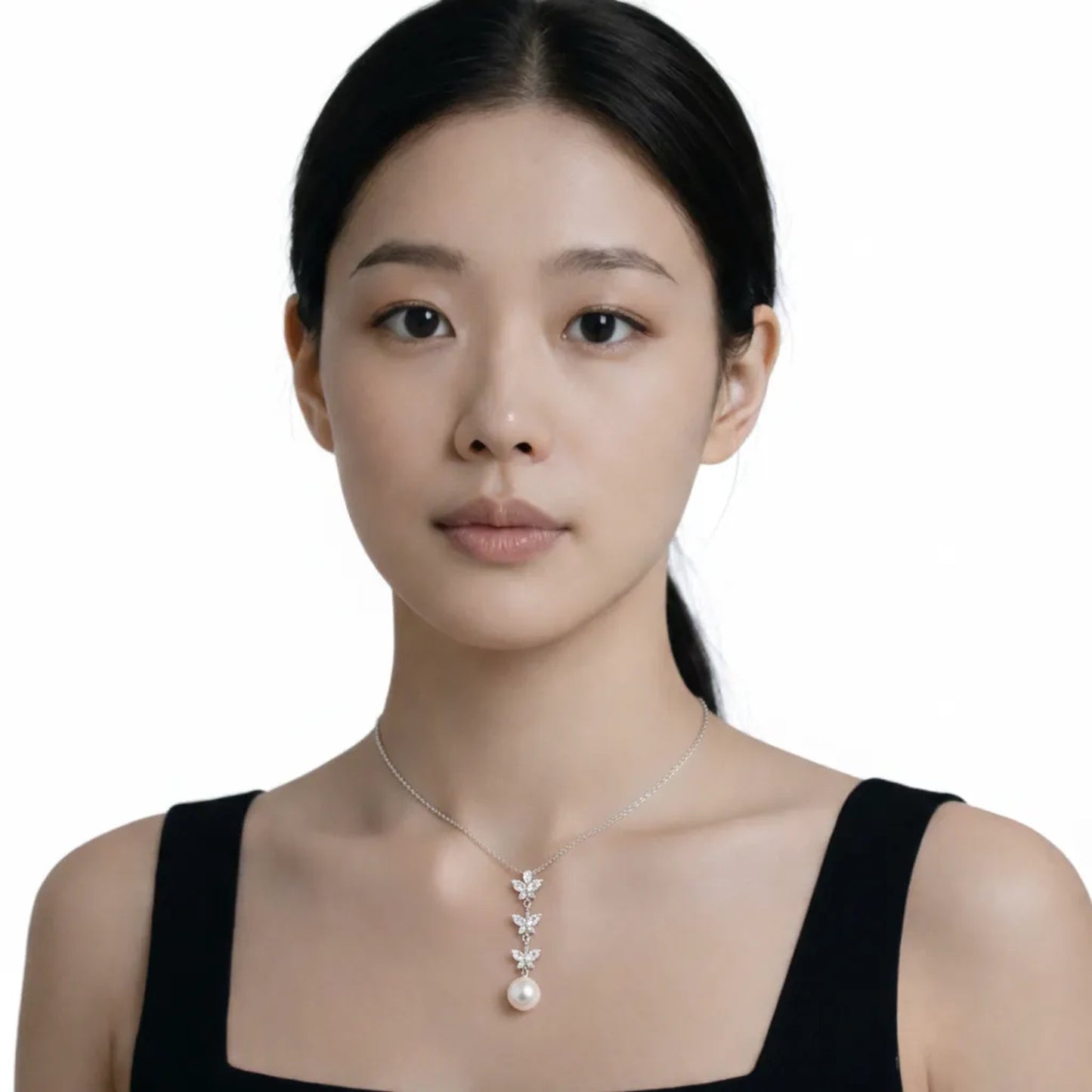Model shot captures a butterfly drop cubic zirconia and pearl pendant, styled with a black square-neck dress so the pendant stays centered at the neckline.