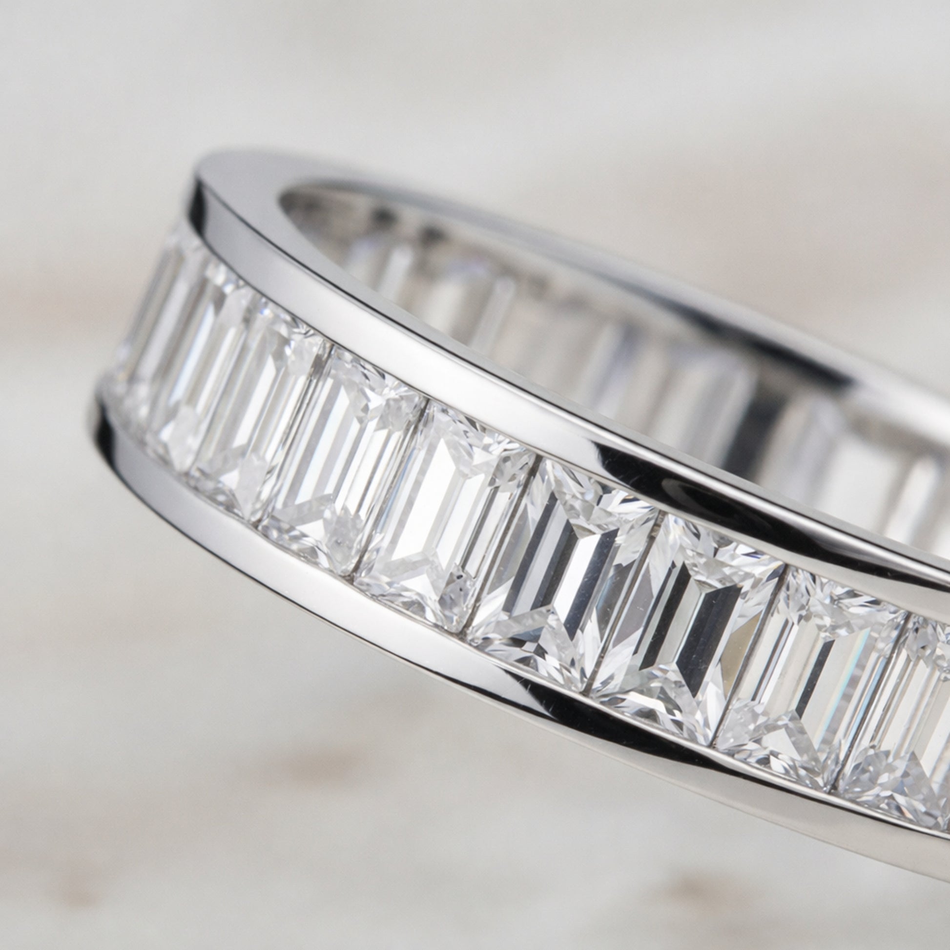 Angled view of the channel set baguette cut cubic zirconia ring emphasizing the straight baguette cut stones and smooth silver tone finish.