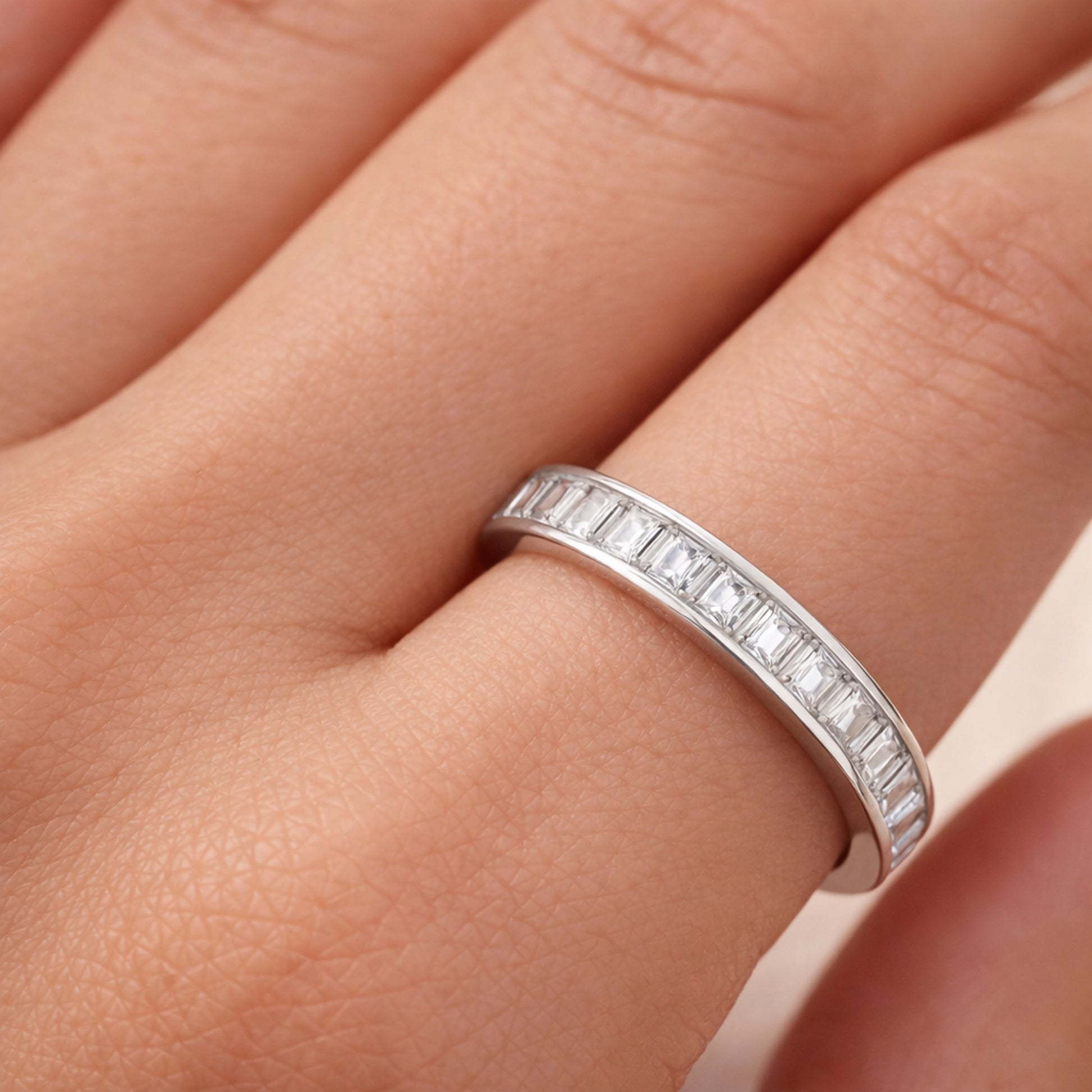 Close up worn on hand view of the channel set baguette cut cubic zirconia ring focusing on the rectangular stone cuts and precise channel setting.