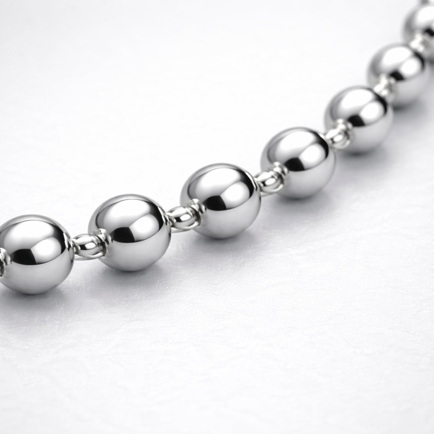 Macro view highlighting the smooth spherical beads and reflective silver tone finish of the necklace.