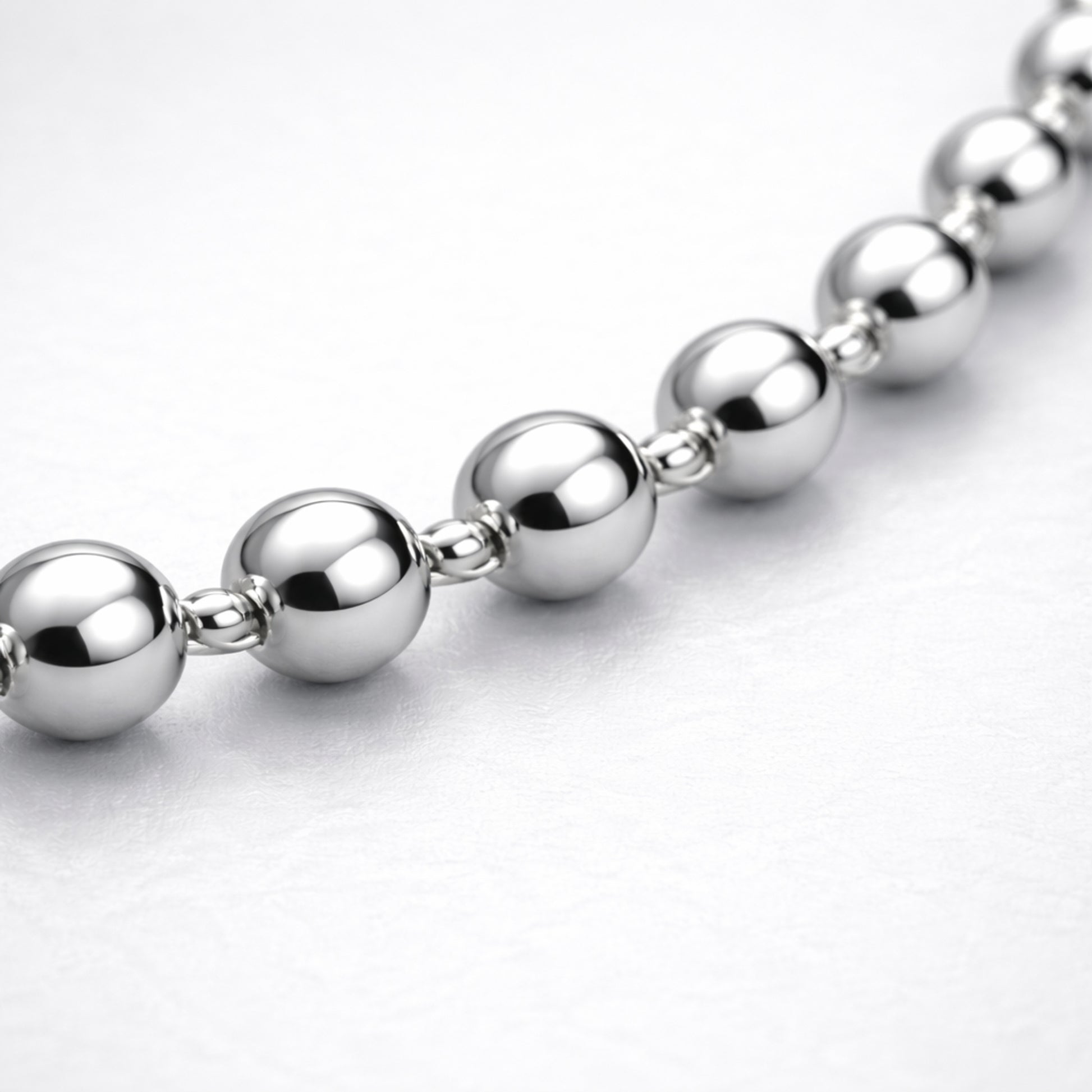 Macro view highlighting the smooth spherical beads and reflective silver tone finish of the necklace.
