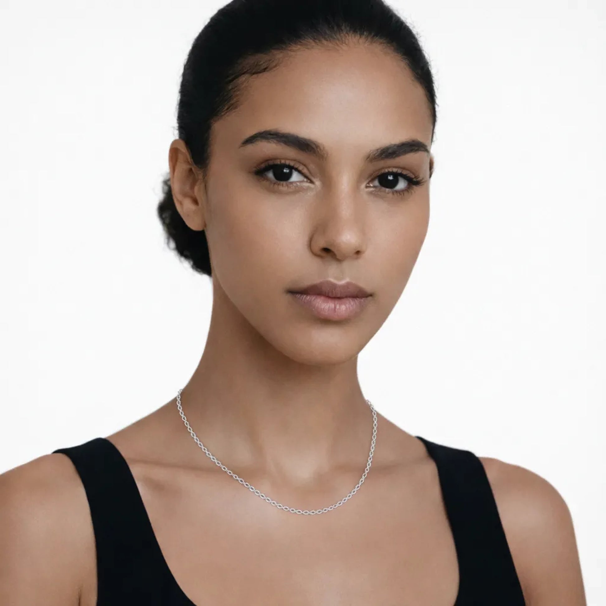On-model portrait highlights a silver tone classic cable chain necklace, styled with a black tank neckline so the chain drapes cleanly along the collarbone.