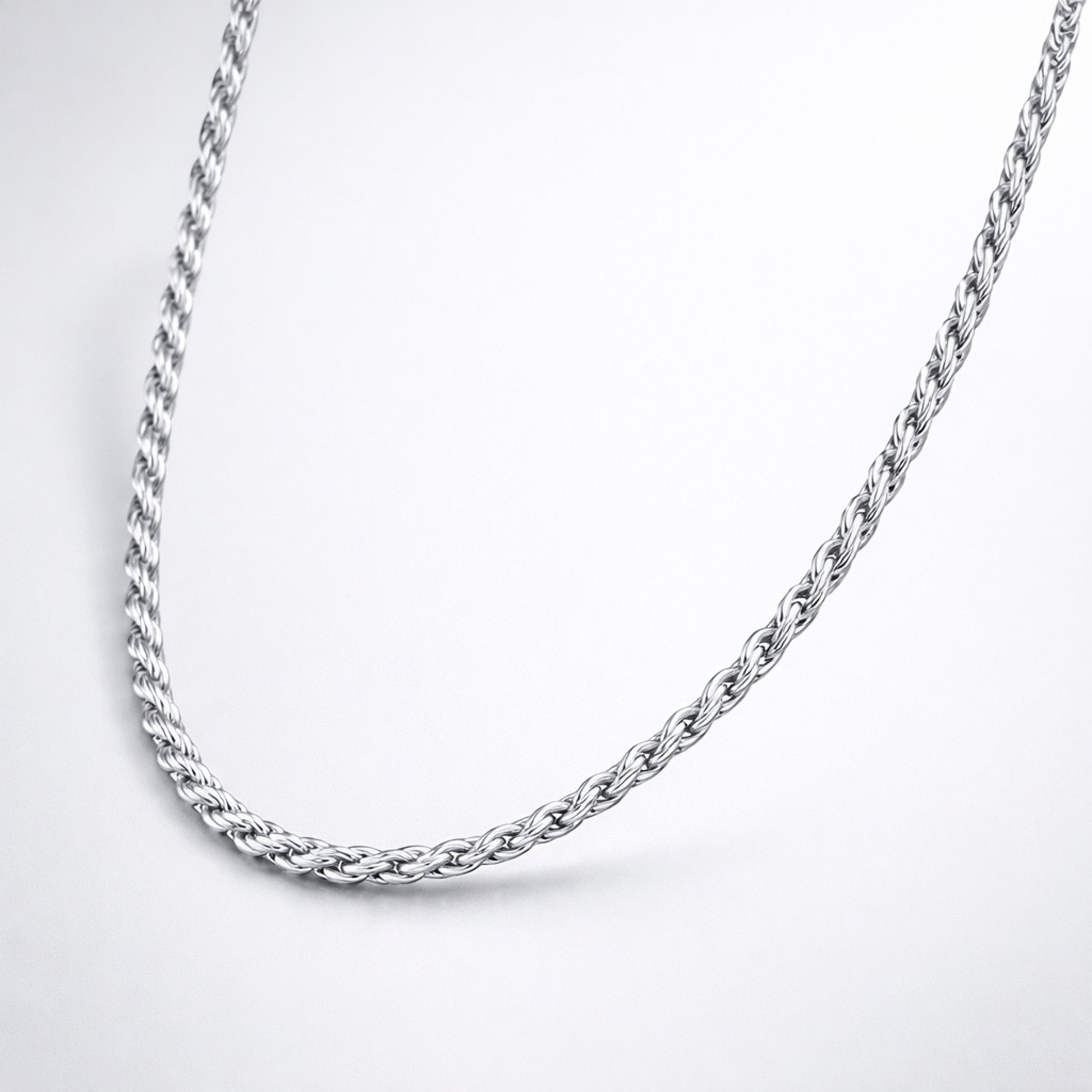 Studio view of the rope chain necklace arranged in a curved shape, showing a consistent braided pattern in silver tone.