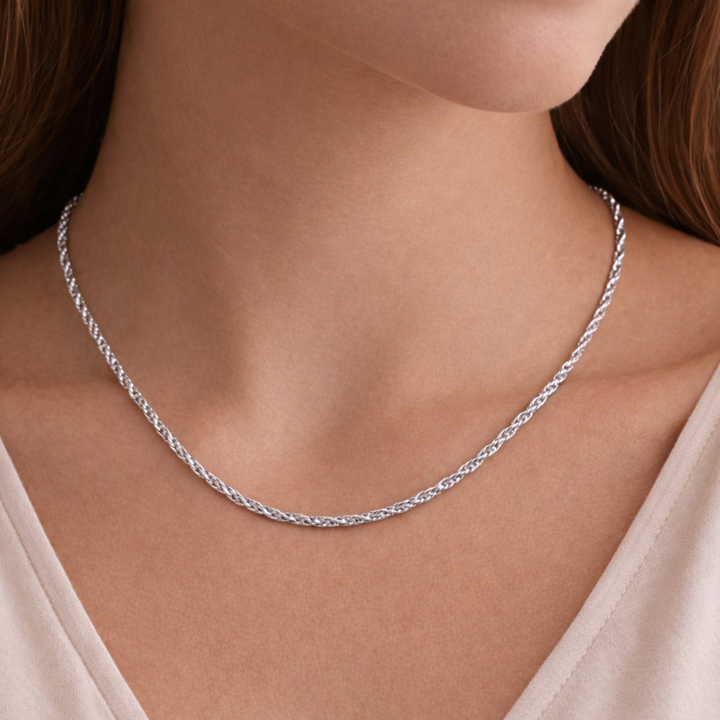 Angled view of the rope chain necklace worn on the neck, showcasing the braided twisted links and reflective silver tone surface.
