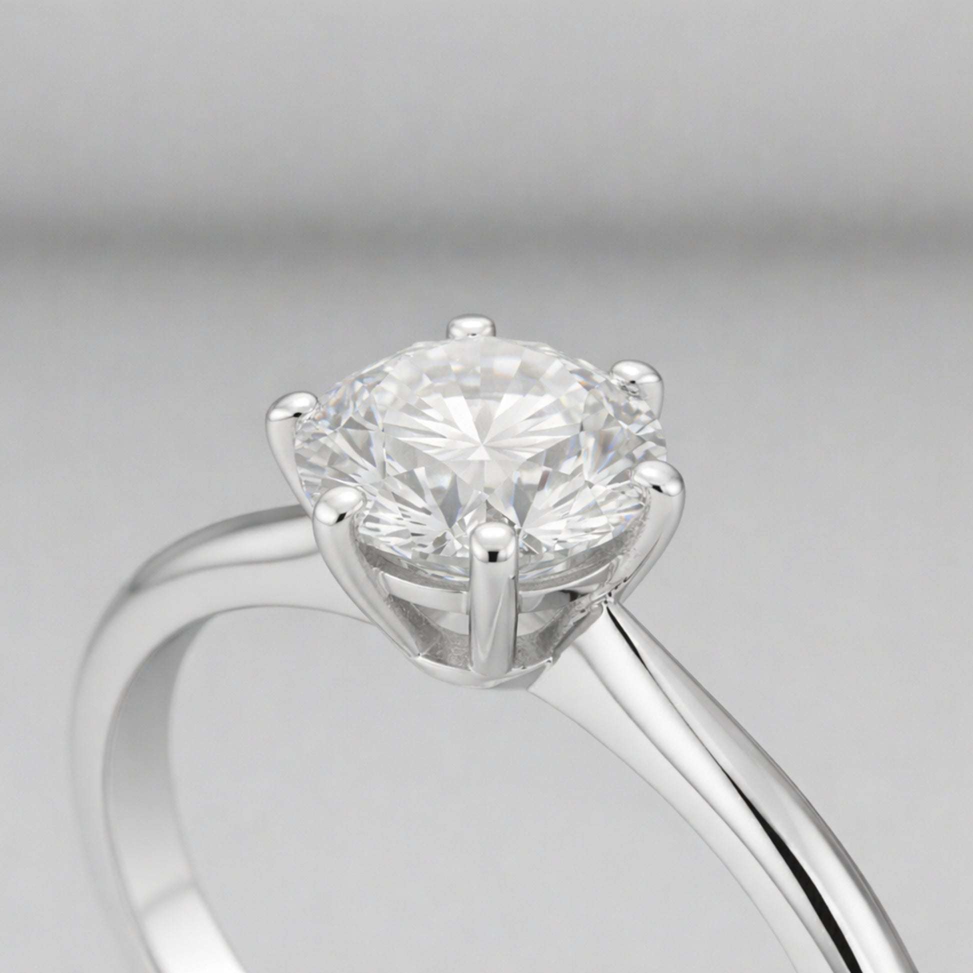 Side profile close up view of the classic solitaire cubic zirconia ring focusing on the raised prong setting, polished silver tone band and the round cut center stone.