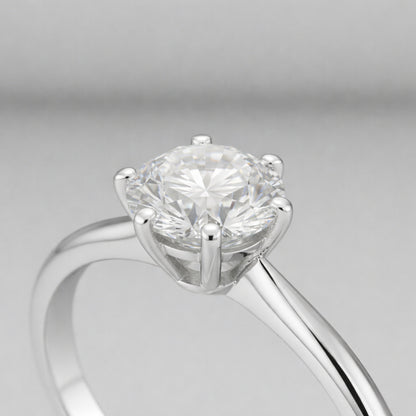 Side profile close up view of the classic solitaire cubic zirconia ring focusing on the raised prong setting, polished silver tone band and the round cut center stone.