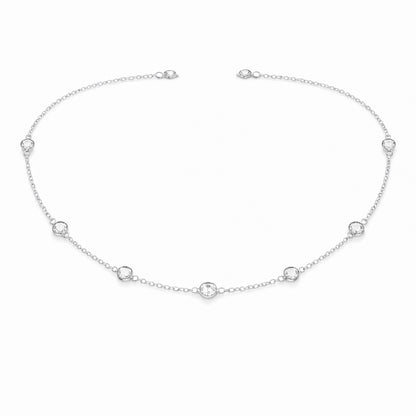 Angled studio view of the silver tone station necklace highlighting the refined chain links and round bezel set stone details.