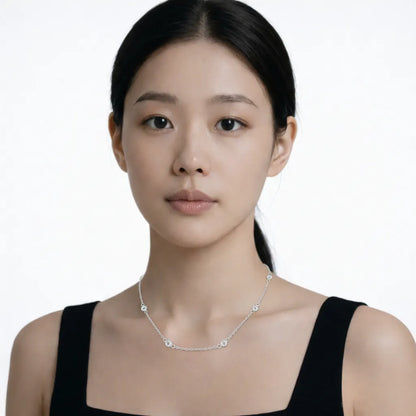 Model shot captures a classic station necklace with bezel set stones, styled with a black sleeveless dress so the chain drapes cleanly along the collarbone.