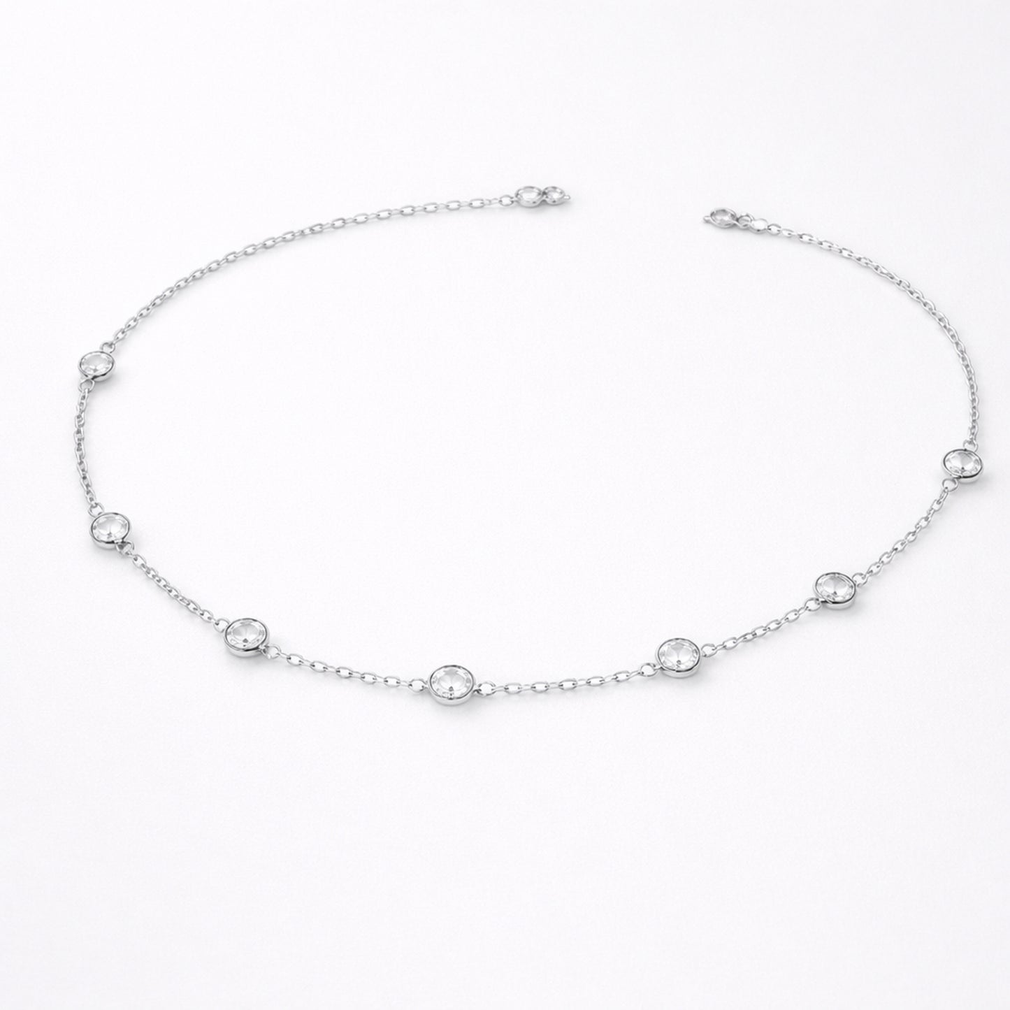 Styled lifestyle image of a station necklace worn close to the collarbone, showcasing the elegant placement of bezel set stones in silver tone.