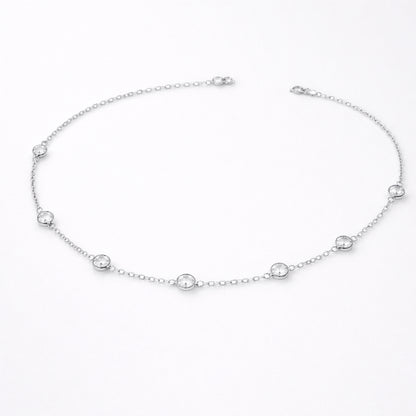 Styled lifestyle image of a station necklace worn close to the collarbone, showcasing the elegant placement of bezel set stones in silver tone.