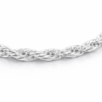 Close up detail of the twisted chain necklace focusing on the intertwined strands and smooth polished silver tone surface.