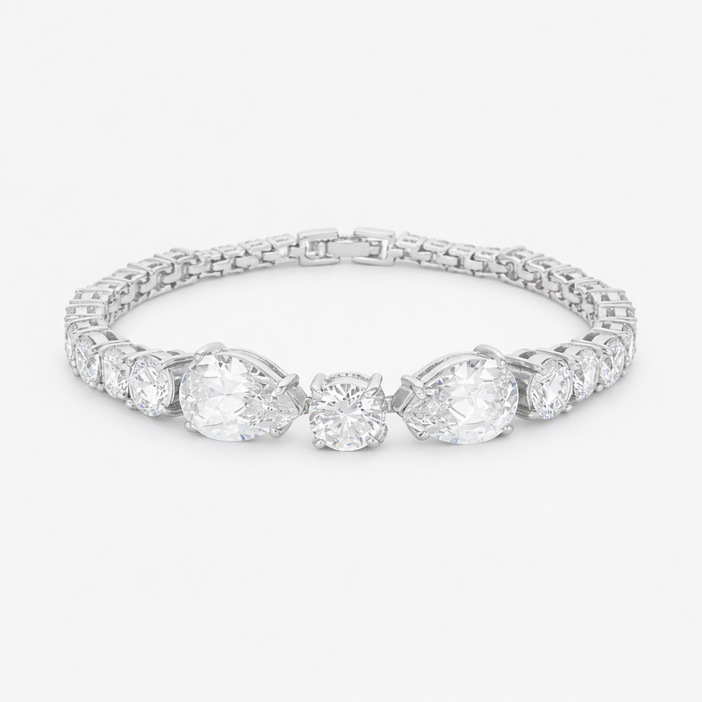 Studio view of a tennis bracelet featuring pear and round cut cubic zirconia set in rhodium plated brass.