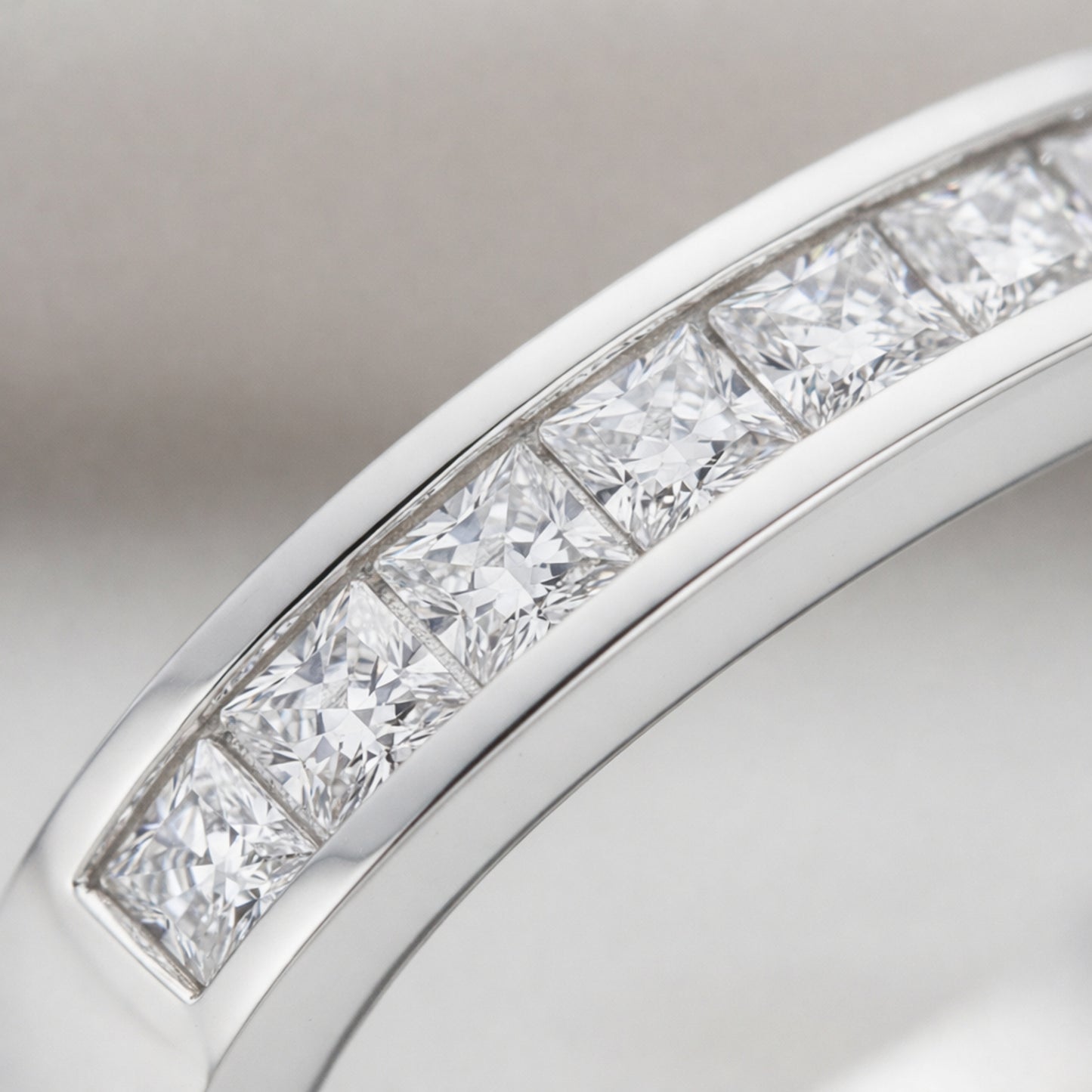 Detailed close up of channel set cubic zirconia stones arranged in a straight row within a polished Silver Tone band.