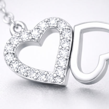 Close up view of the double heart pendant highlighting the pavé set heart and the polished open heart design.