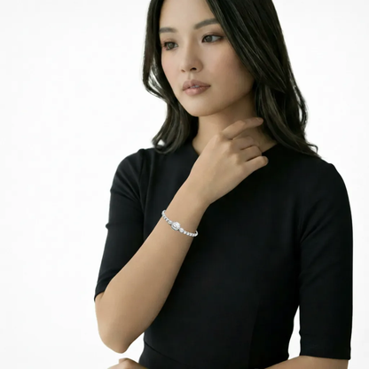 Model shot shows a halo-slider bracelet with a raised round center and a line of cubic zirconia stones, styled against a black short-sleeve dress for crisp contrast.