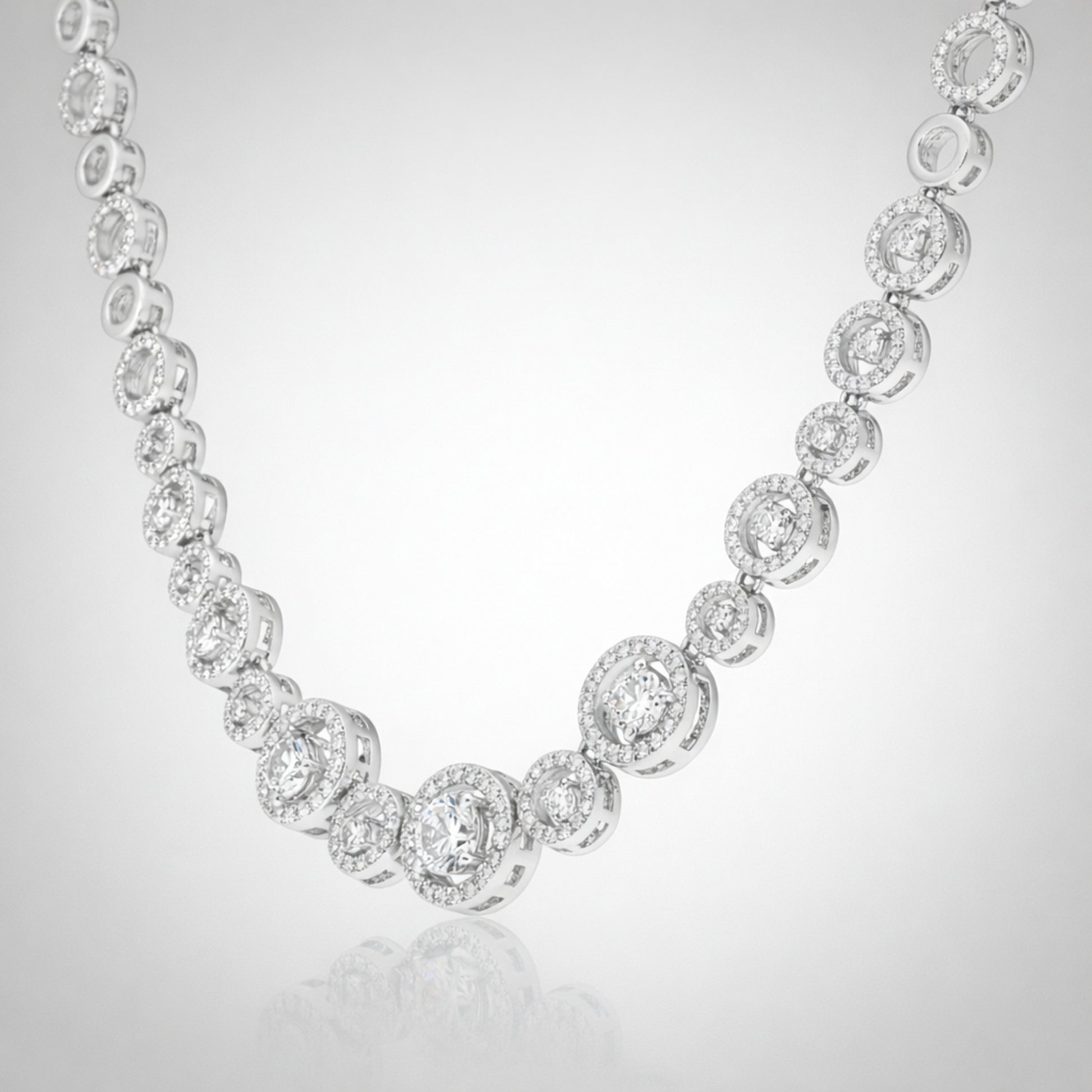 Angled studio view of a halo style silver tone necklace emphasizing the symmetrical stone arrangement.