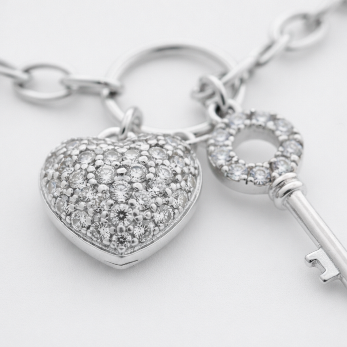 Close up view of the heart charm with cubic zirconia stones, showing the polished rhodium plated brass surface.