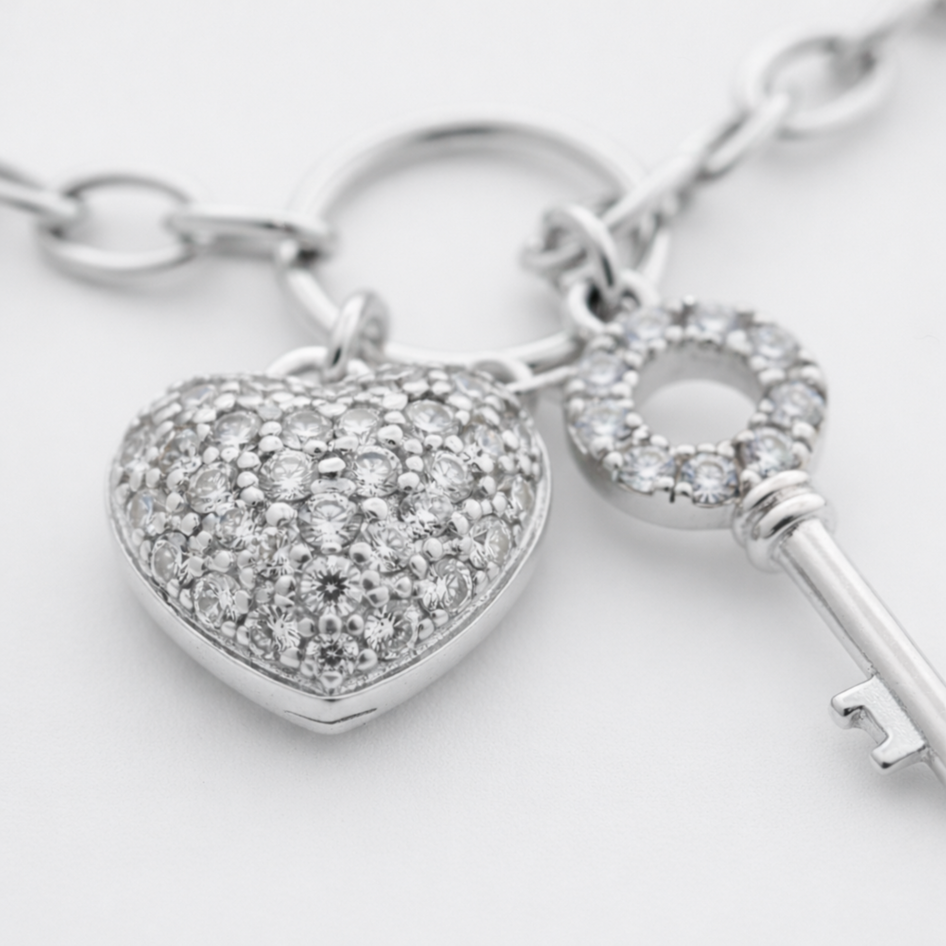 Close up view of the heart charm with cubic zirconia stones, showing the polished rhodium plated brass surface.