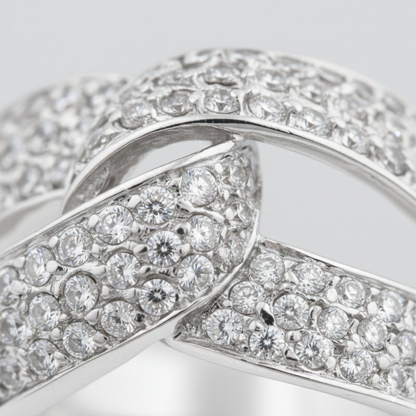 Close up view of an infinity pavé cubic zirconia ring in silver tone finish, highlighting the continuous infinity design and pavé set stones along the band.