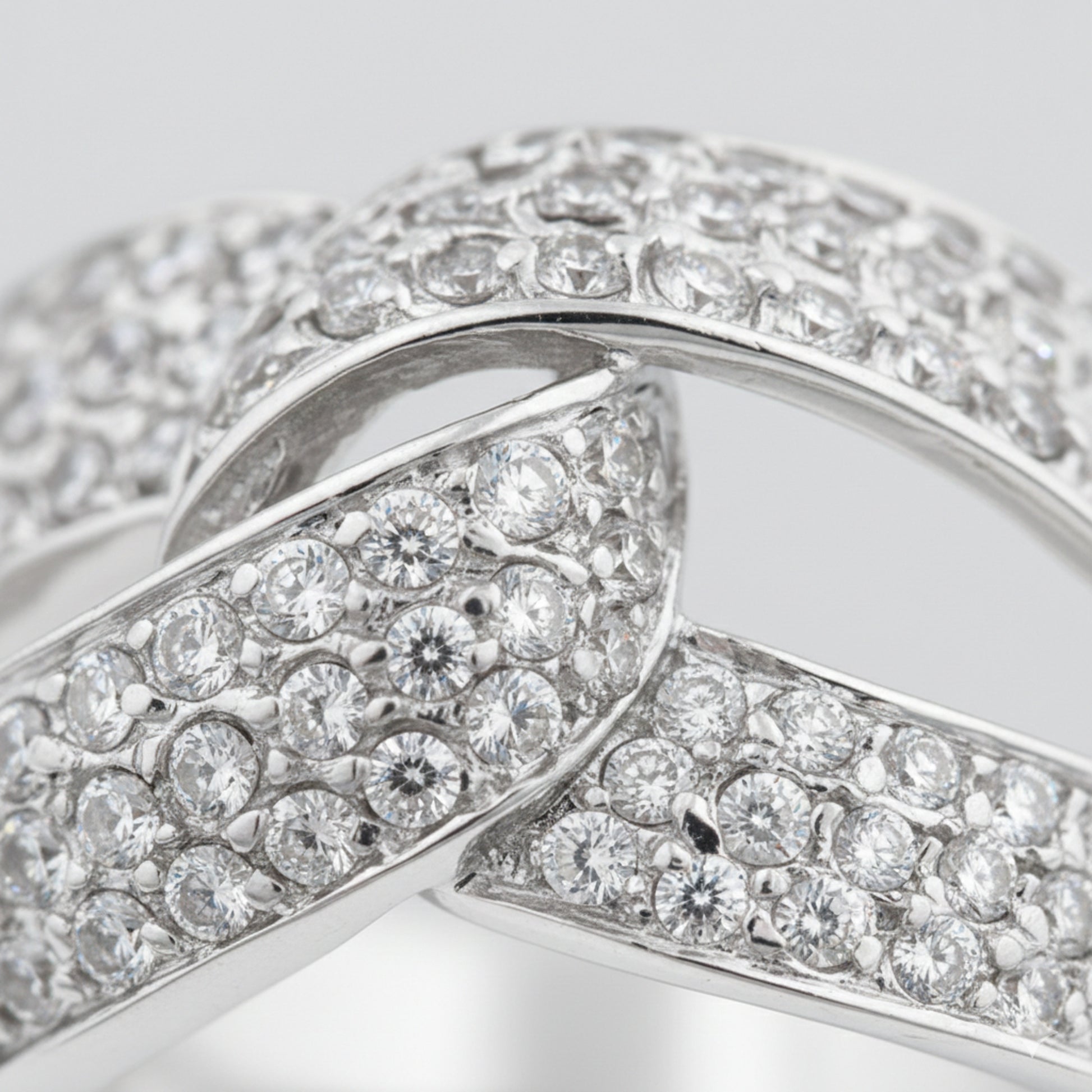 Close up view of an infinity pavé cubic zirconia ring in silver tone finish, highlighting the continuous infinity design and pavé set stones along the band.