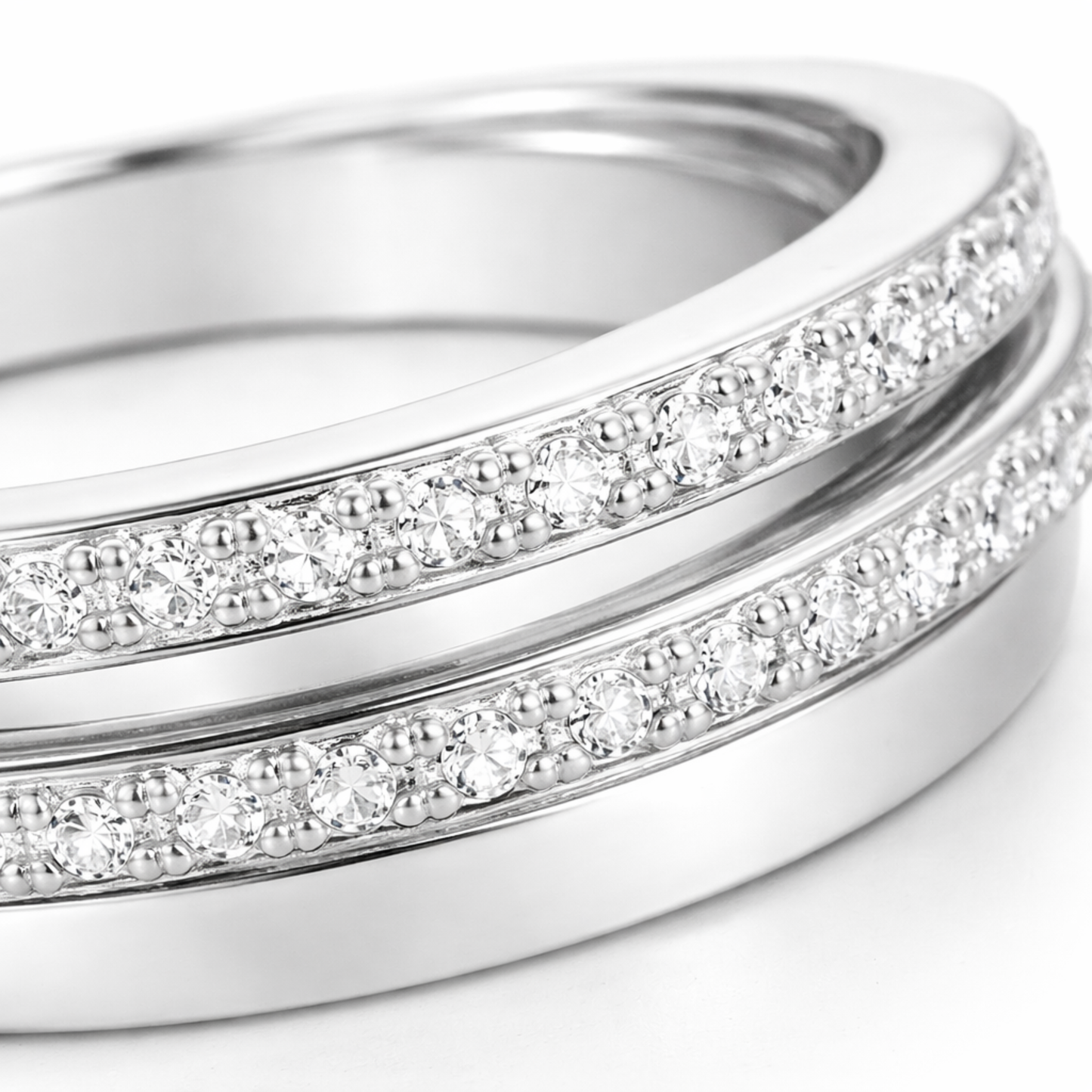 Close up view of the intertwined silver tone bands highlighting the pavé set round cut cubic zirconia stones arranged closely along two of the bands.
