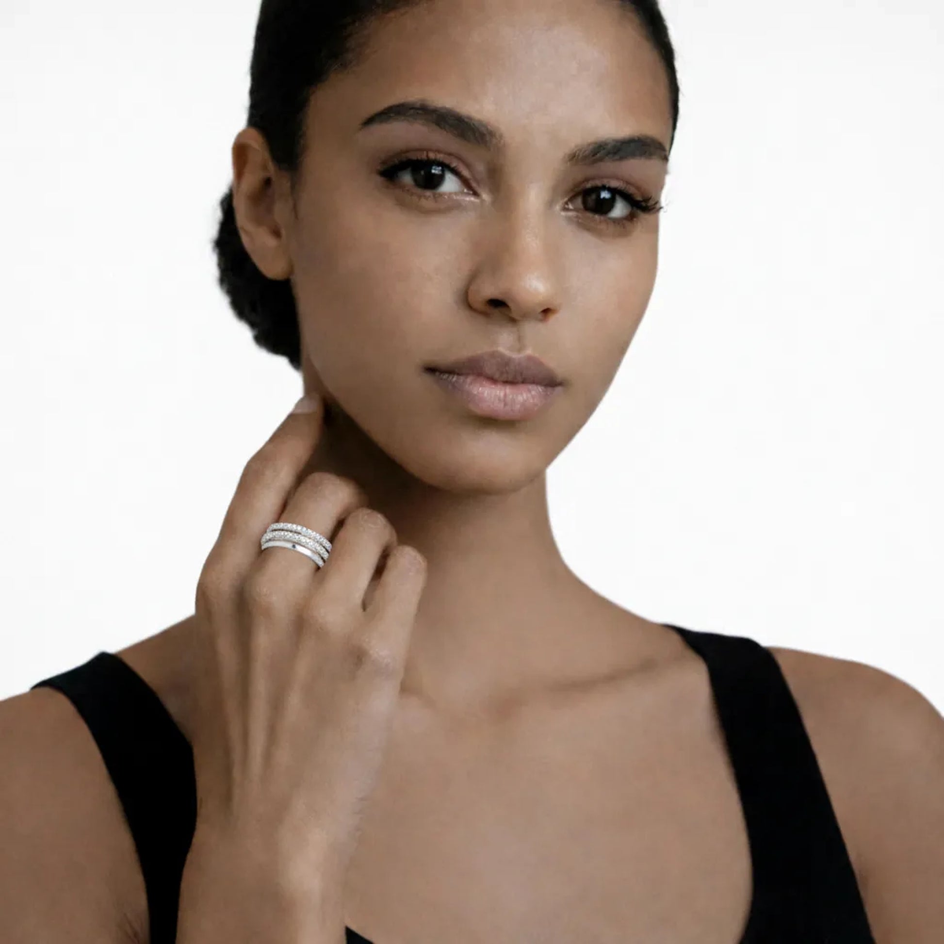 On-model portrait highlights a intertwined band ring with cubic zirconia, styled with a black sleeveless top so the ring sparkles along the fingertips.