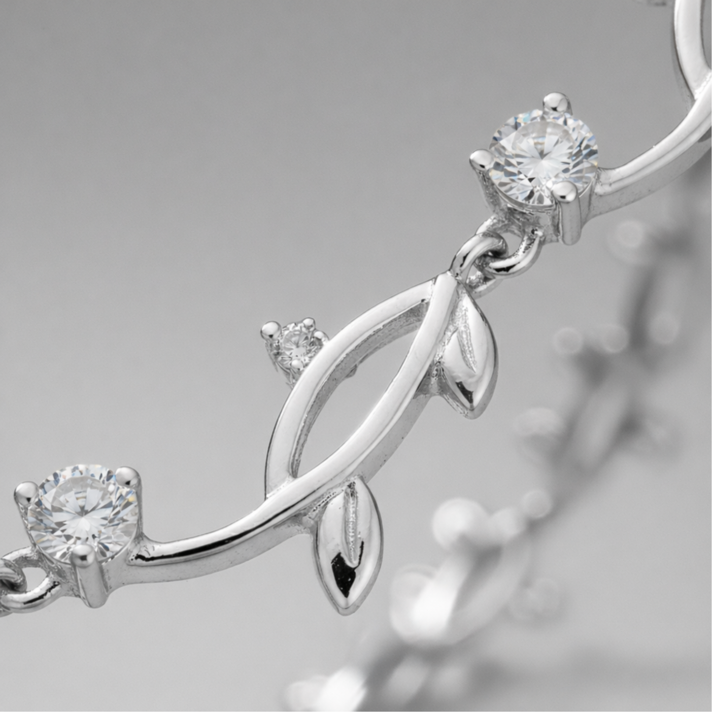 Close up detail of the leaf motif links with cubic zirconia accents and polished silver tone finish.