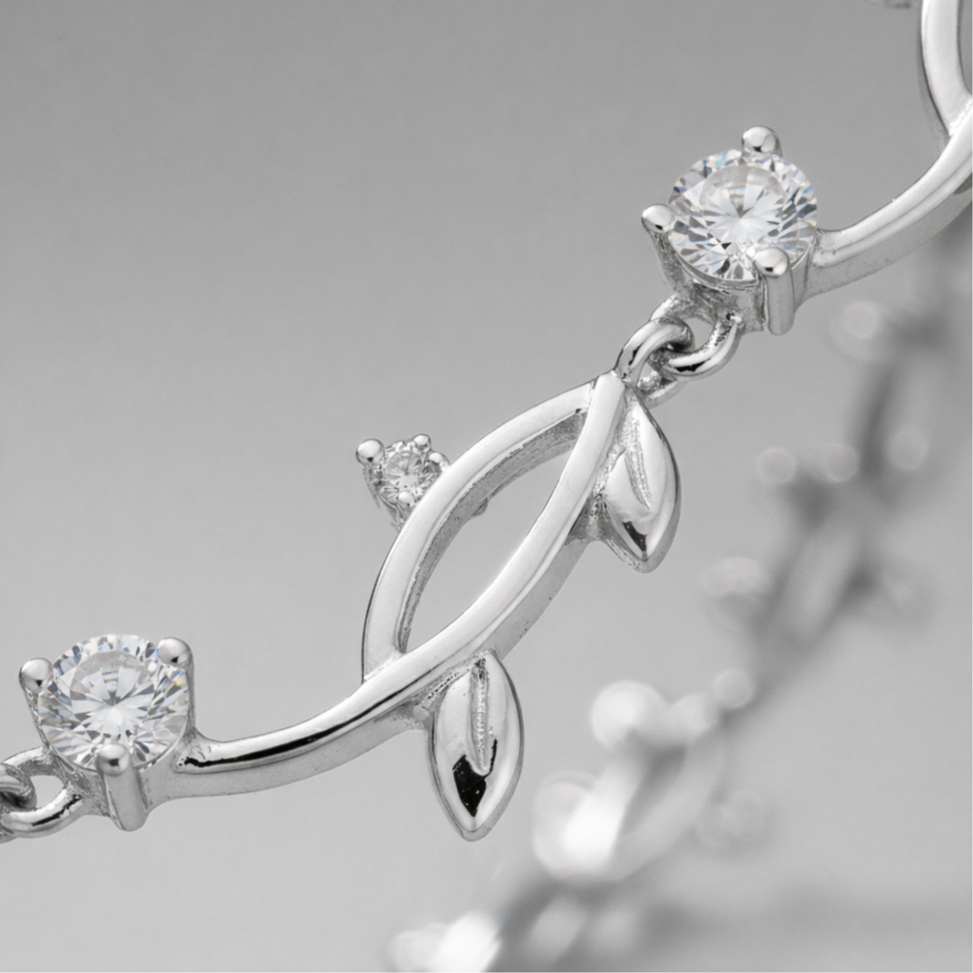 Close up detail of the leaf motif links with cubic zirconia accents and polished silver tone finish.