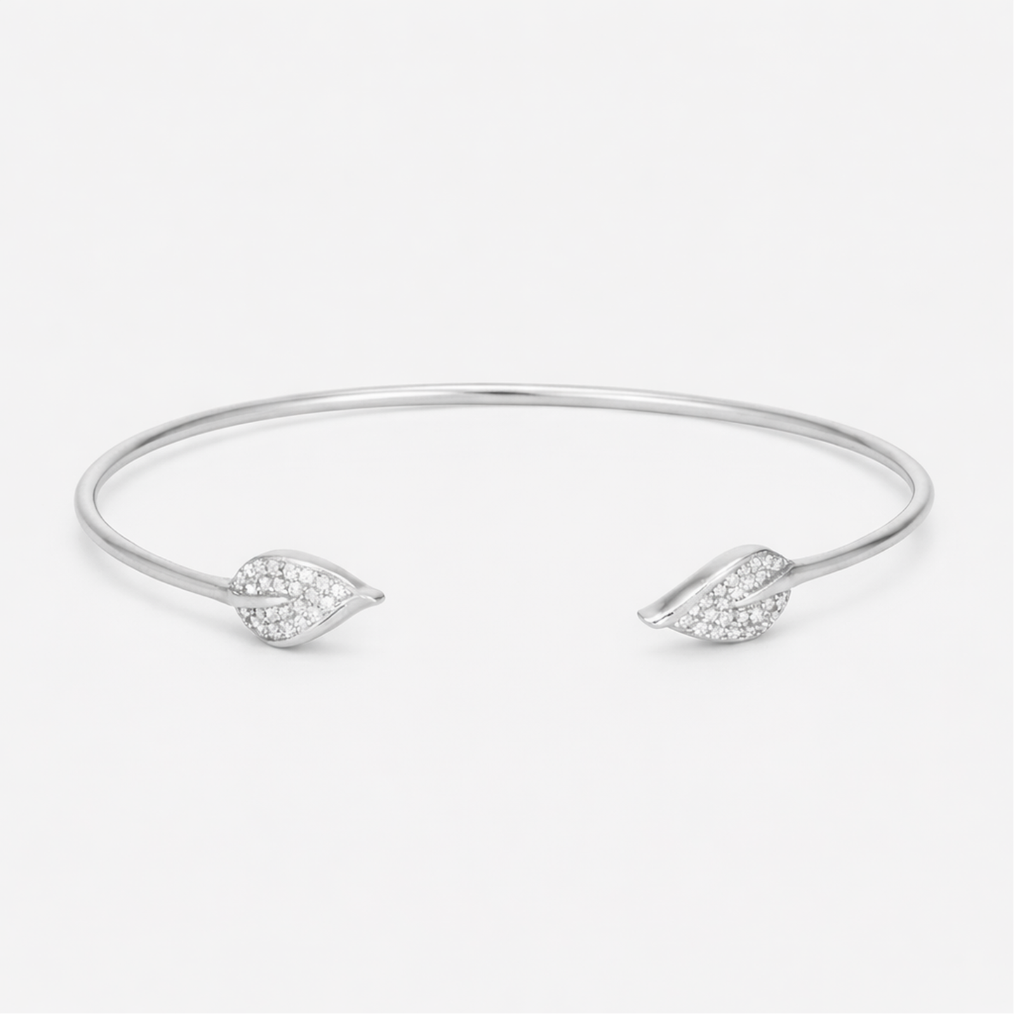 Front view of an open silver tone cuff bracelet featuring a smooth polished surface and cubic zirconia accents on both ends.