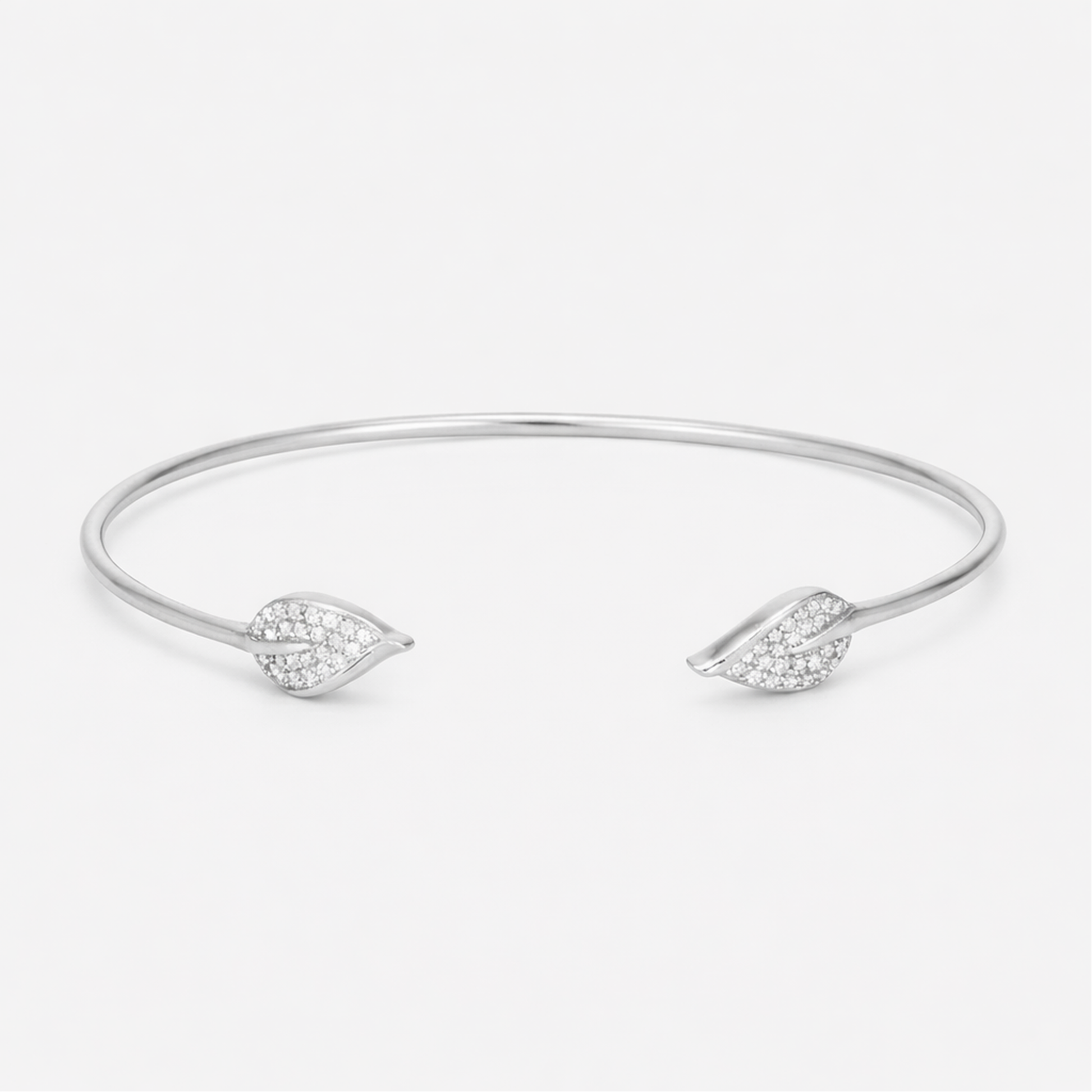 Front view of an open silver tone cuff bracelet featuring a smooth polished surface and cubic zirconia accents on both ends.