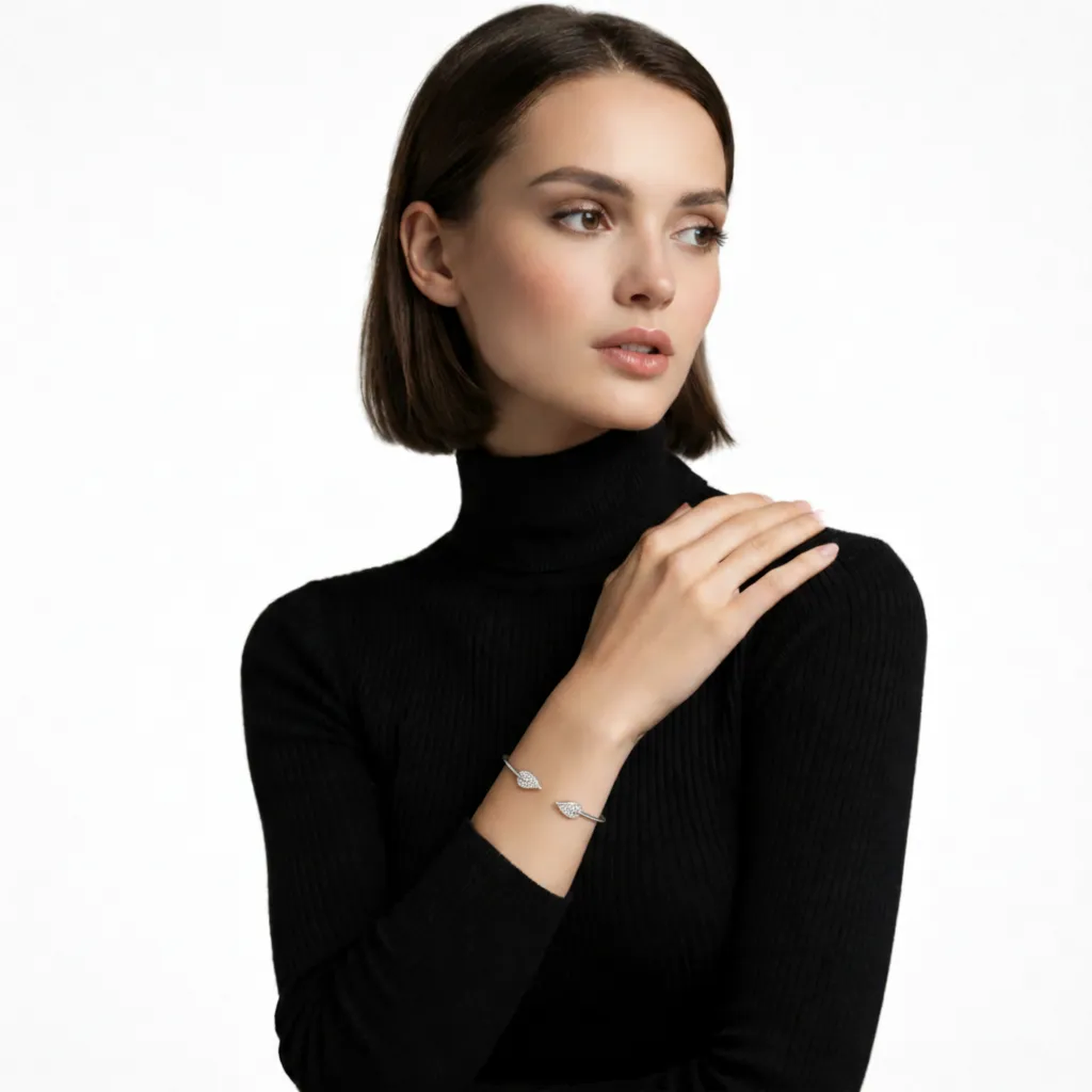 Model view of a slim silver tone open cuff ending in pavé leaf tips, stacked over a black ribbed turtleneck to emphasize the slip-on sparkle around the wrist.