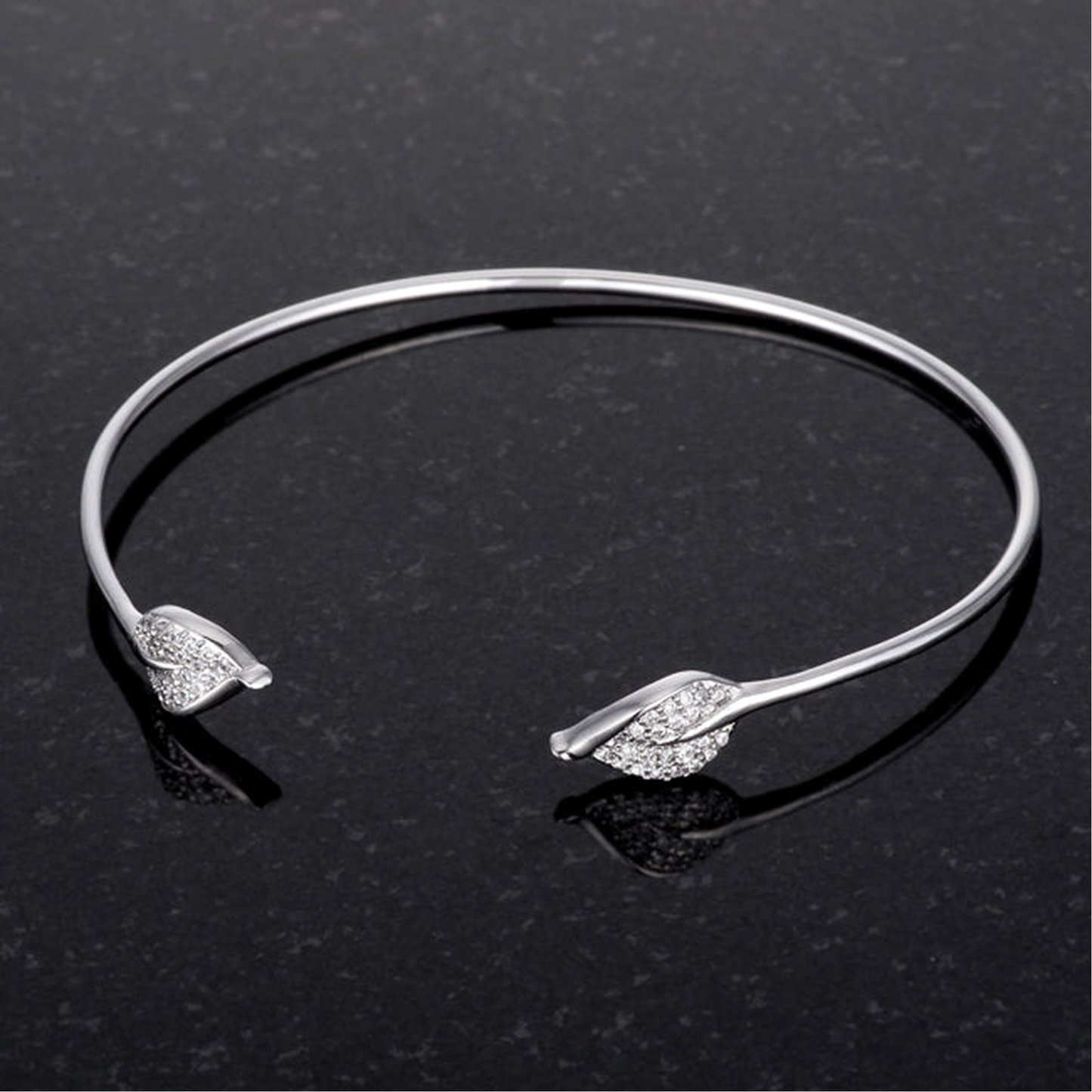 Studio image of an open cuff bracelet in silver tone with clear cubic zirconia accents.