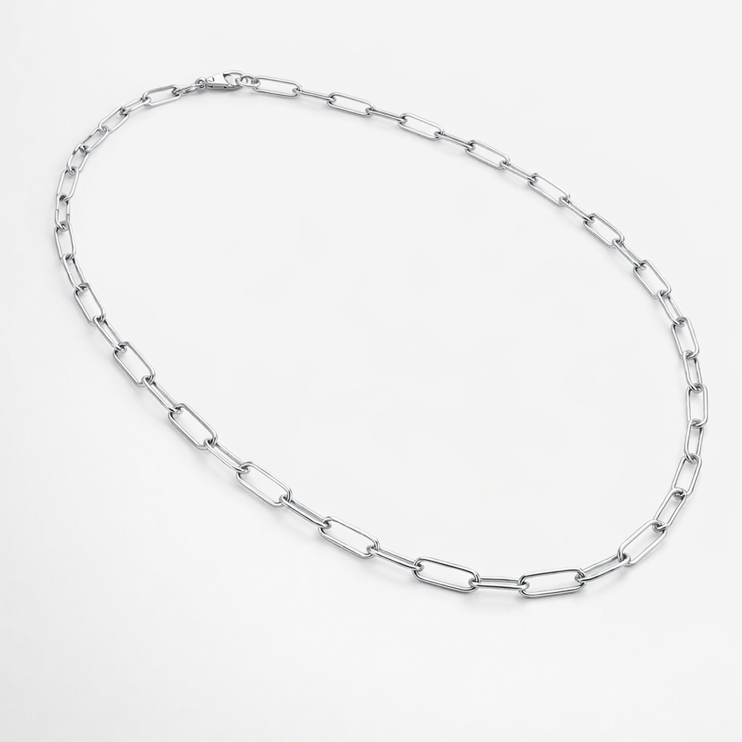 Flat lay product image of a silver tone paperclip chain necklace displaying its modern minimalist design.