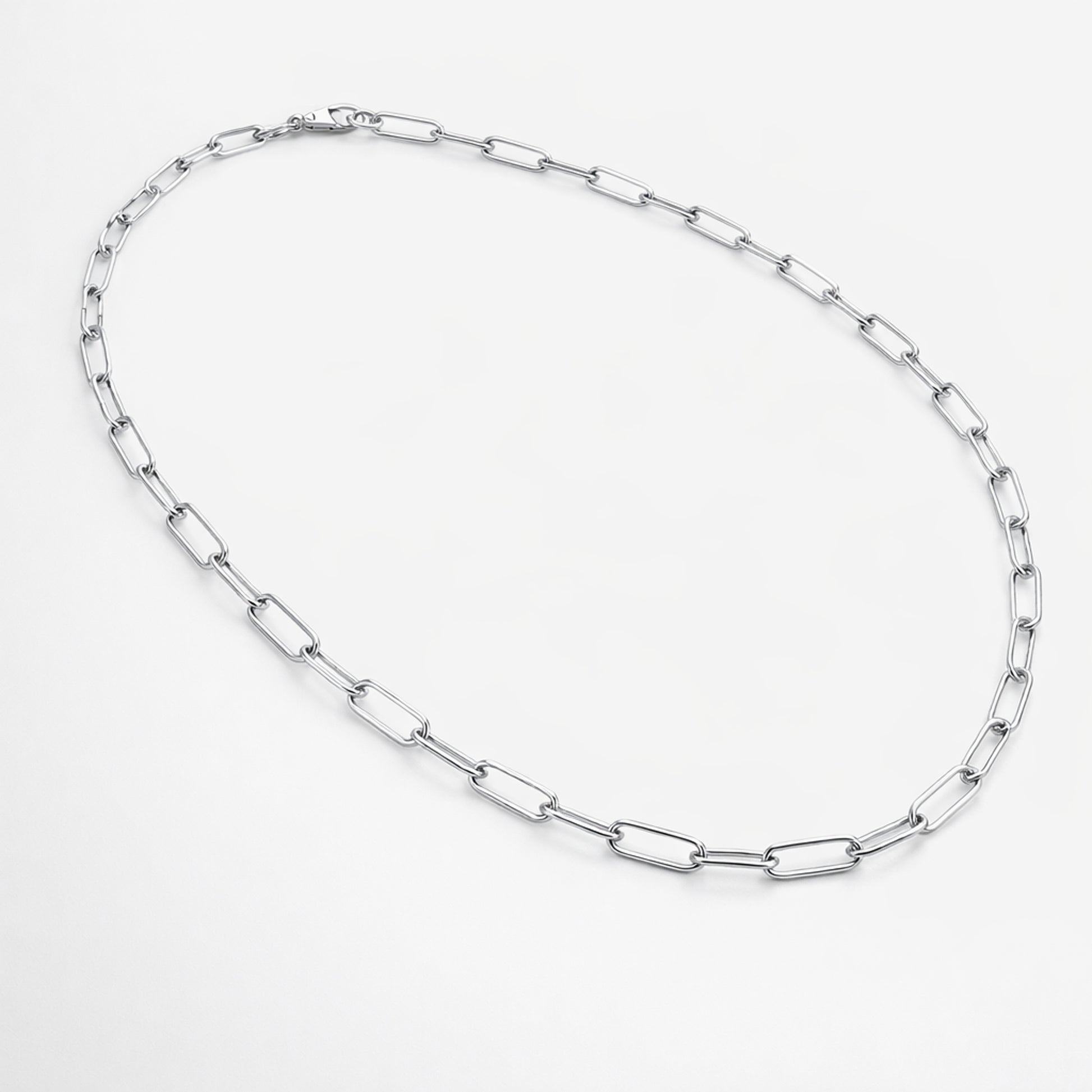 Flat lay product image of a silver tone paperclip chain necklace displaying its modern minimalist design.