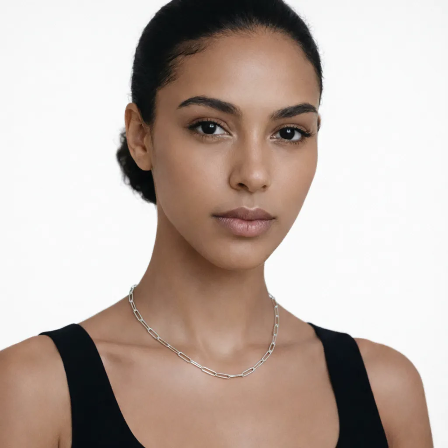 On-model portrait highlights a silver tone paperclip chain necklace, styled with a black tank neckline so the chain drapes cleanly along the collarbone.