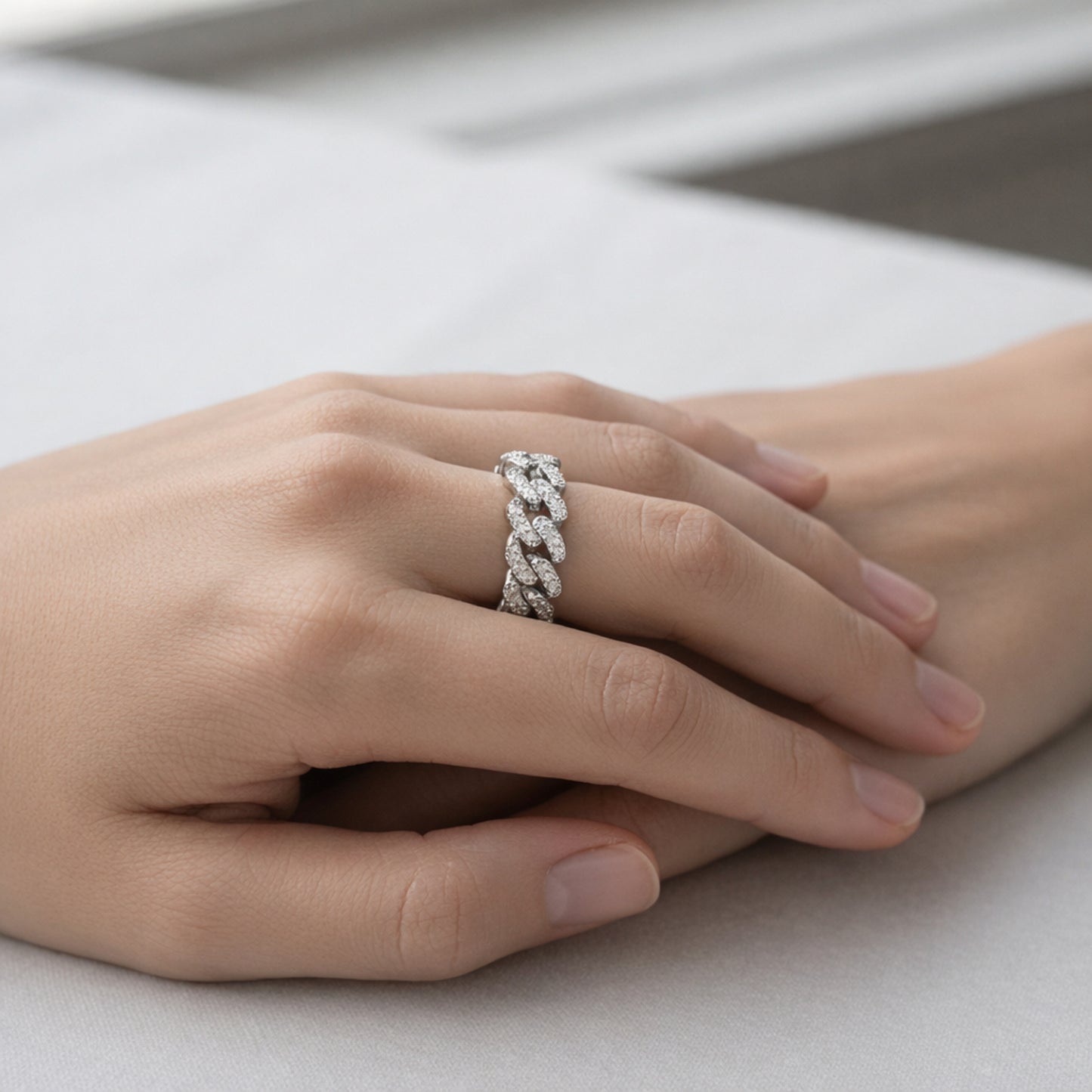 Lifestyle view of a pavé chain link cubic zirconia ring in silver tone finish worn on the hand in a relaxed setting.