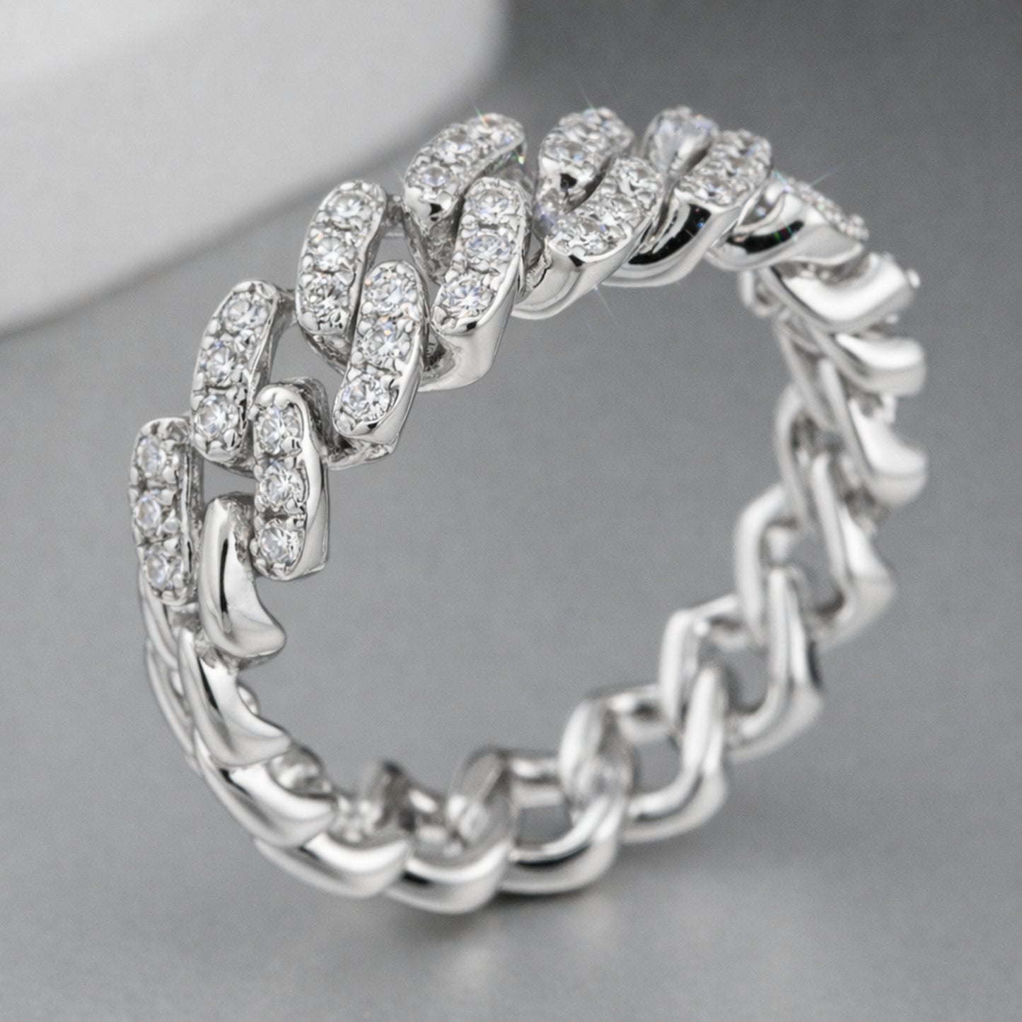 Studio view of a pavé chain link cubic zirconia ring in silver tone finish displayed against a neutral background.