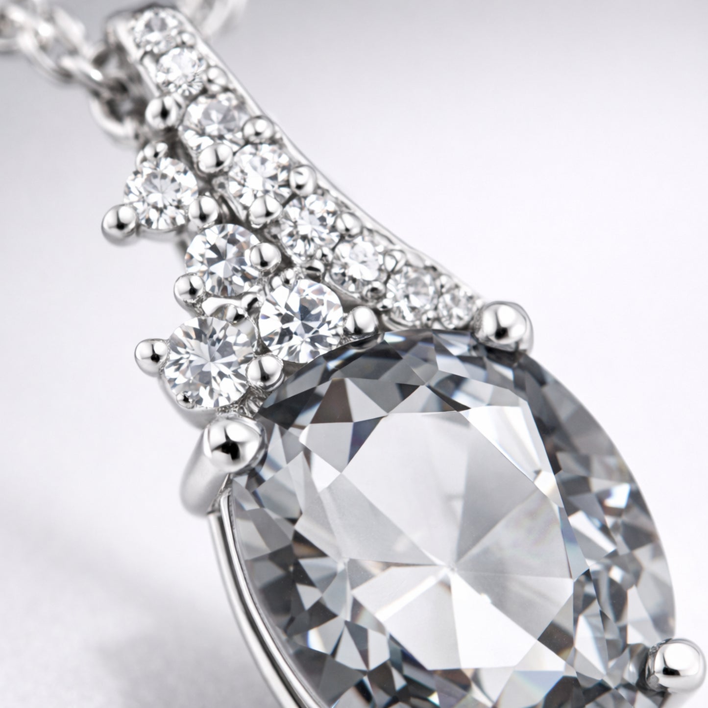 Close up view of the pear cut cubic zirconia pendant focusing on the faceted stone and silver tone prong setting with accent stones.