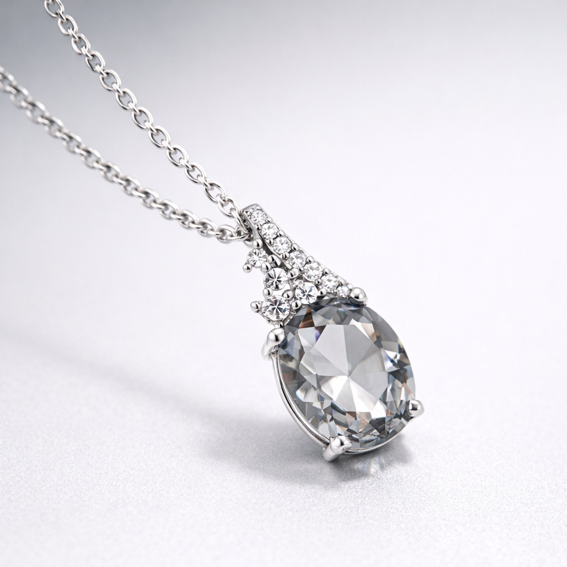 Detail view highlighting the side profile of the pear cut cubic zirconia pendant and the silver tone setting with small accent stones.