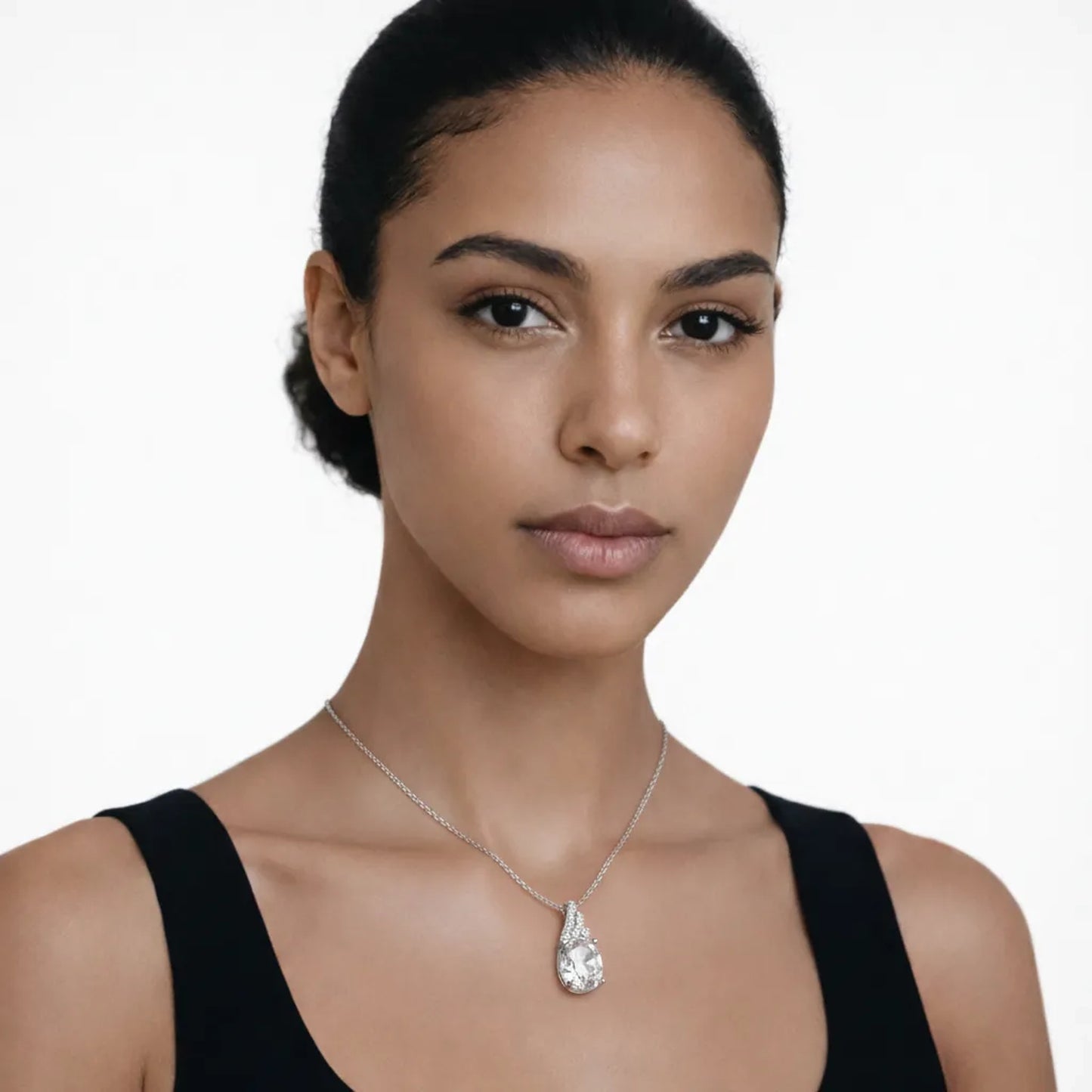 On-model portrait highlights a silver tone pear cut cubic zirconia pendant, styled with a black scoop-neck top so the pendant stays centered at the neckline.