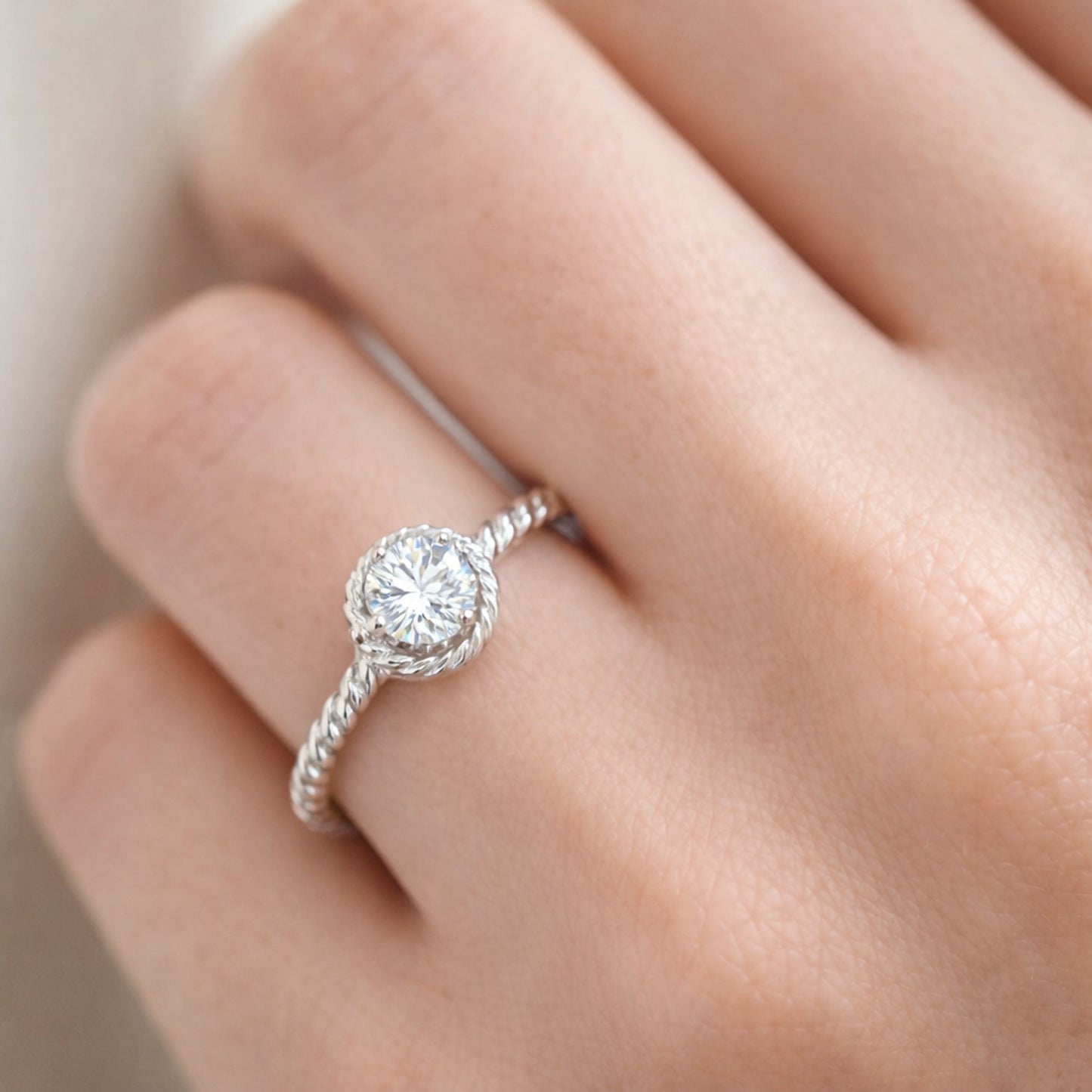 Close up worn on hand view of the rope style solitaire cubic zirconia ring focusing on the round center stone and refined twisted band texture.