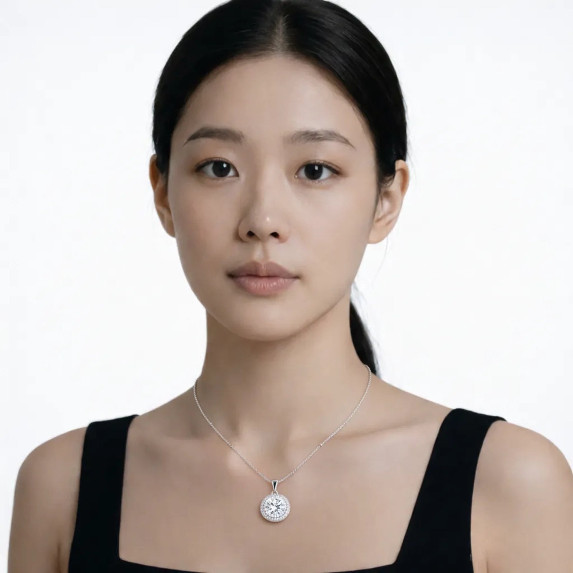 Model shot captures a silver tone round halo cubic zirconia pendant, styled with a black square-neck dress so the pendant stays centered at the neckline.