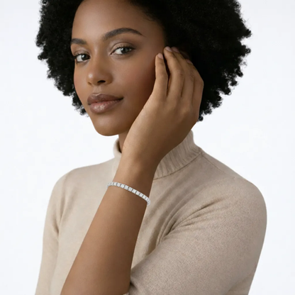 On-model portrait showcases a classic cubic zirconia tennis bracelet circling the wrist with uniform stones, paired with a beige knit and warm skin for soft shine.