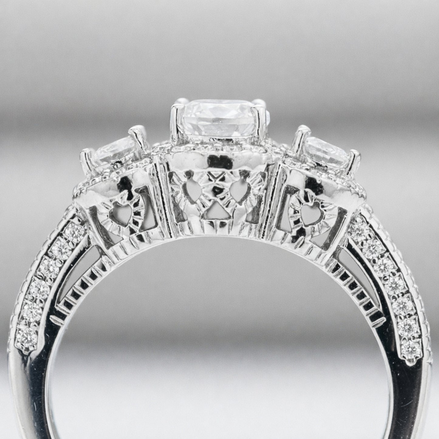 Side profile view of the three stone halo cubic zirconia ring highlighting the gallery details and pavé set shoulders.
