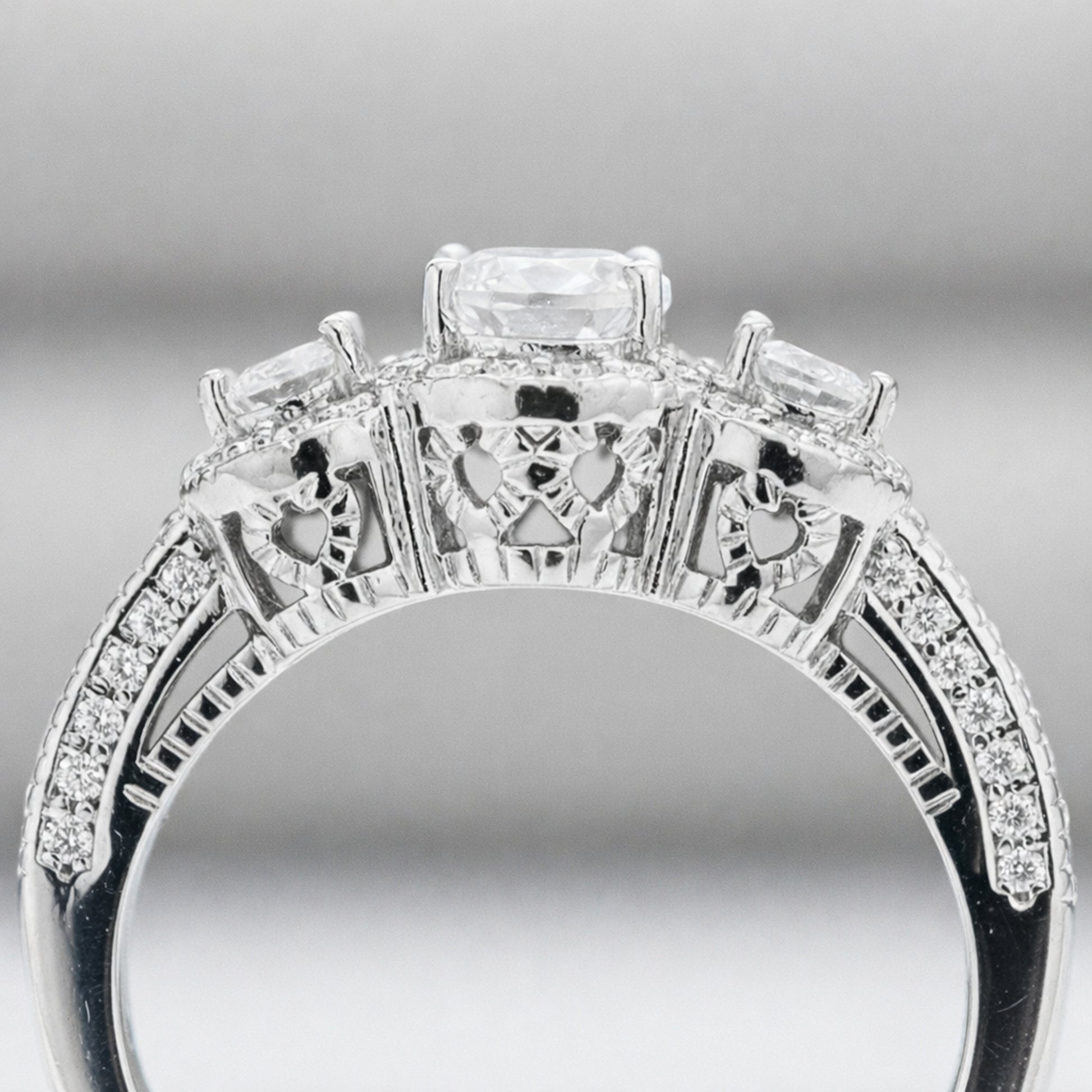 Side profile view of the three stone halo cubic zirconia ring highlighting the gallery details and pavé set shoulders.
